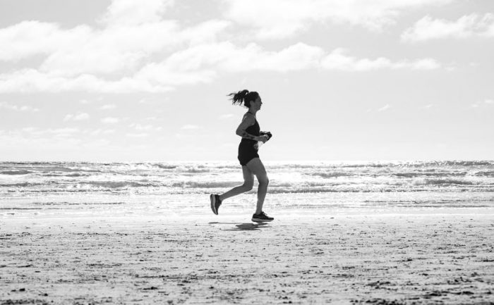 A woman jogging on La Lucila del Mar beach, Argentina in a monochrome setting. Capturing fitness and freedom.